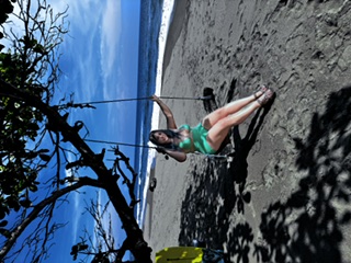 Guest on a beach swing under a tree