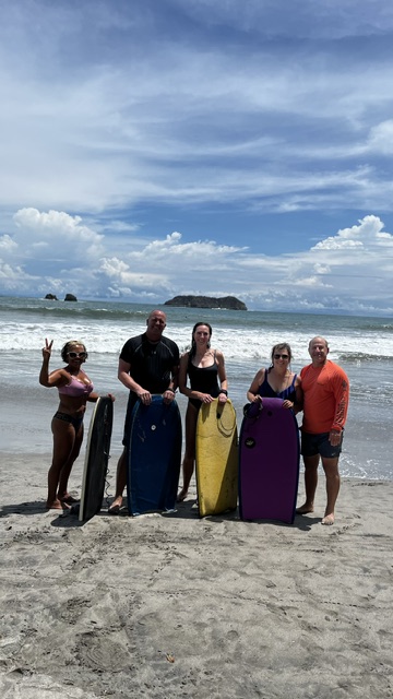 Group of guests with bodyboards on the beach