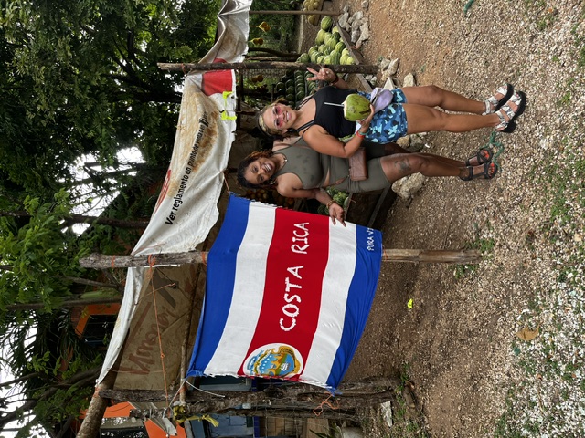 Guests posing by a Costa Rica flag at a fruit stand