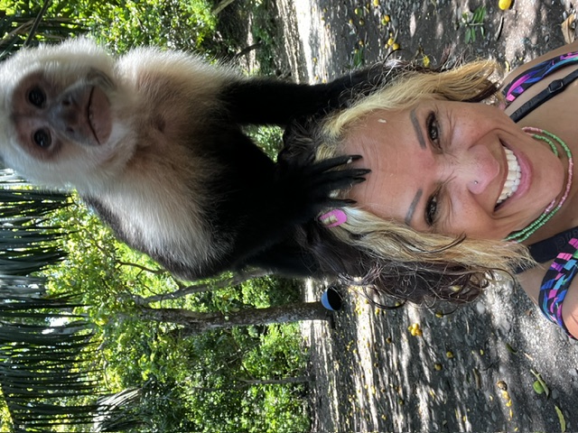 Scheyla laughing with a capuchin monkey perched on her head